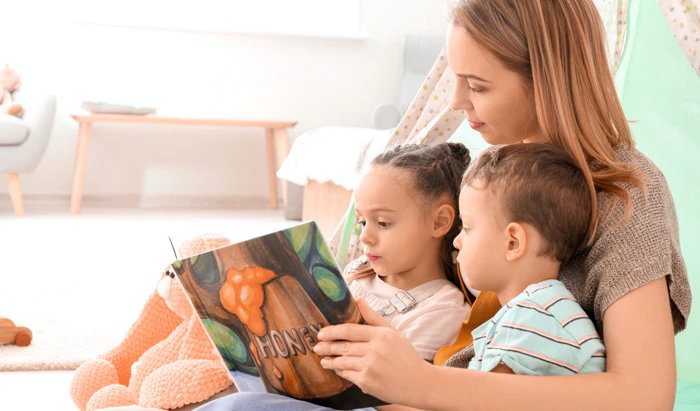 A young woman reading to two little kids.