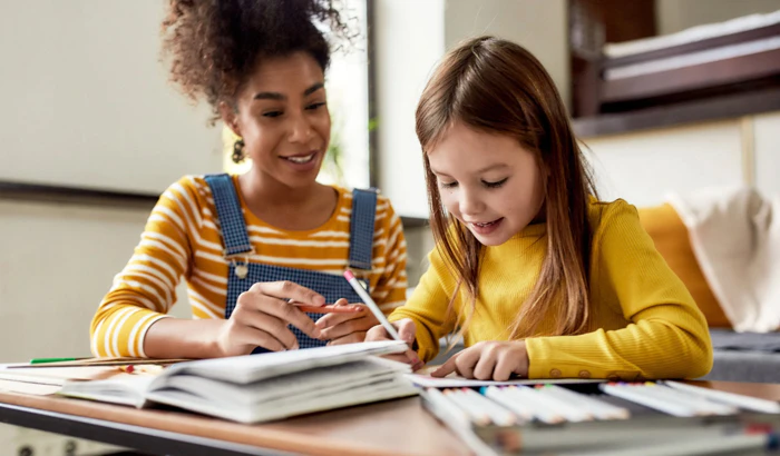 A woman helping a little girl do her homework.