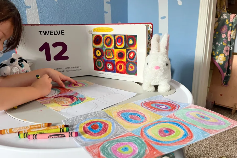 Child coloring concentric circles with crayons and number book nearby.