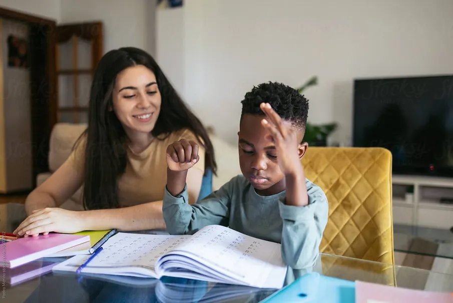 Woman helping a child with homework at a table in the living room.