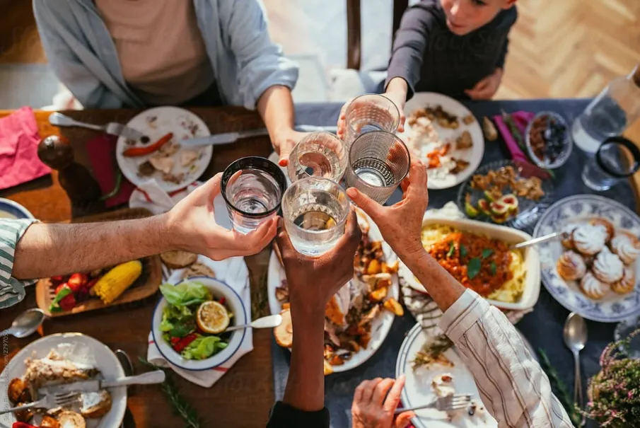 A group of people clinking glasses over a diverse dinner table setting.