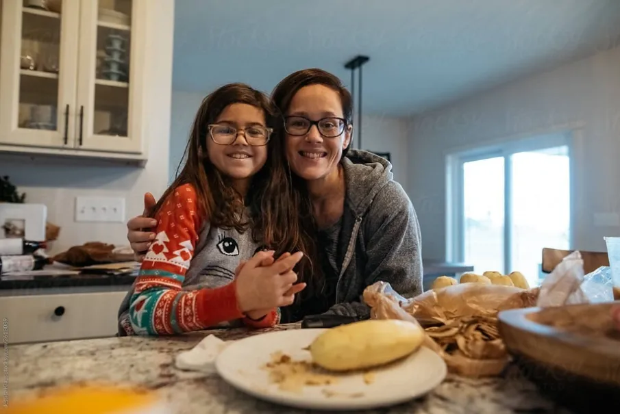 Mother and daughter smiling in kitchen preparing food